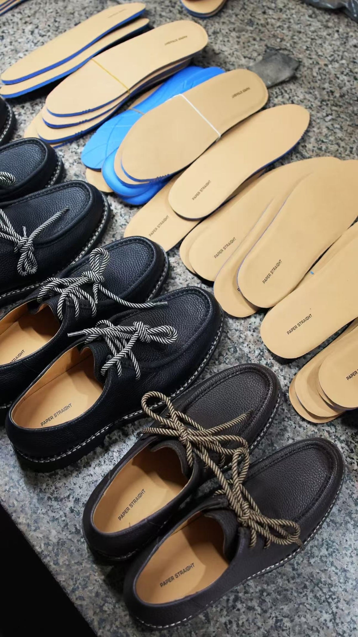 Paper Straight insoles and finished derbies laid out on the factory floor