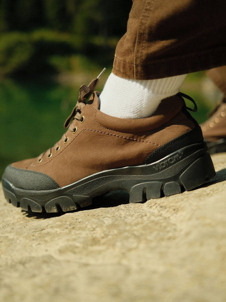 Paper Straight Alpine Hiker Brown — worn on a rock above a glacial lake, Swiss Alps