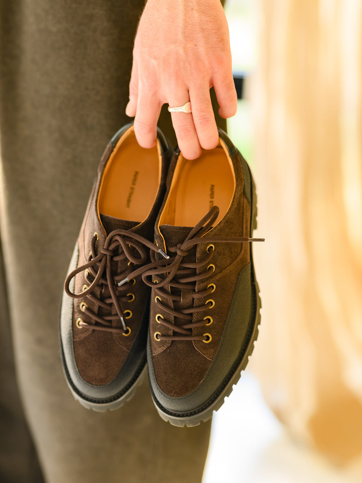 Paper Straight Ridgeworks Low Coffee — pair held by hand, insole logo visible